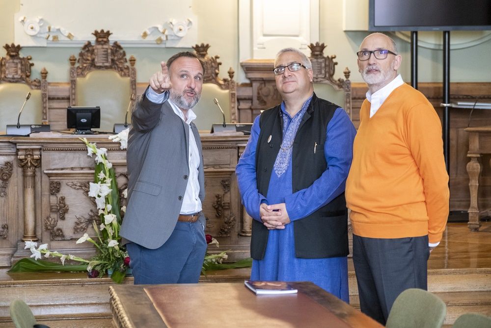 Juan Manuel Guimerans explica a Swamiji y Ramchandani la historia del salón de plenos del ayuntamiento de Valladolid.